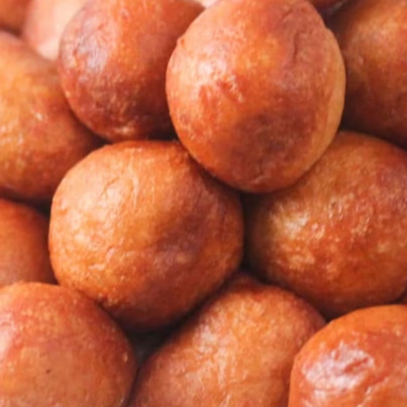 Close-up of a pile of golden-brown, round fried dough balls, likely sweet or savory.