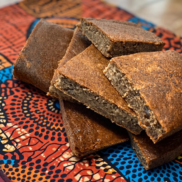 Several pieces of brown, square-cut bread with a textured interior, on a colorful patterned cloth.